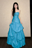Woman wearing a blue strapless gown with a textured wall background