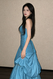 Woman in a blue evening gown against a plain background