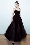 Woman wearing a black evening gown against a light blue background