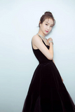 Woman in a black dress posing against a light blue background