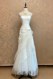 White strapless gown on a mannequin against a beige wall.