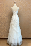 White wedding dress on a mannequin against a beige wall.