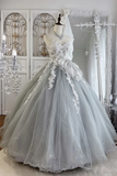 Gray wedding dress with floral details on a mannequin against a decorative wall.