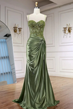 Green evening gown on a mannequin against a white wall.