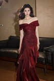 Woman in a red off-shoulder dress standing in an indoor setting.