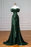 Green evening gown on a mannequin against a white wall.