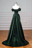 Green evening gown on a mannequin against a white wall.