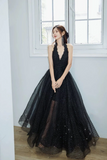 Woman in a black evening gown standing in a room with large windows.