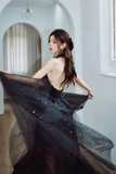 Woman in a black evening gown with sheer overlay in an elegant interior setting