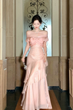 Woman in a pink evening gown standing in an elegant hallway.