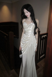 Woman in a white satin dress standing indoors.