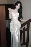 Woman in a white evening gown standing indoors.