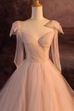 White wedding dress with sheer sleeves on a mannequin against a blurred background