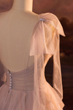 Mannequin wearing a light-colored dress with a sheer bow detail against a blurred background