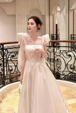Woman in a white dress standing in an elegant interior setting