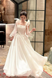 Woman in a white dress with large sleeves in an indoor setting