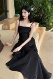 Woman in a black dress sitting outdoors on a stone bench.