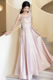 Woman in a pink evening gown standing in an elegant interior setting.