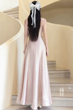 Woman in a long, light-colored dress standing on a staircase with a white bow in her hair.