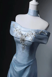 Light blue evening gown with floral embellishments on a mannequin against a dark background