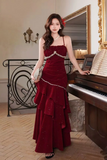 Woman in a red dress standing next to a piano in an elegant room.