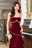 Woman in a red dress with gold accents standing in an elegant room with a piano.