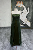 Green evening gown on a mannequin against a decorative wall with a lotus flower.