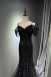 Black evening gown with sheer sleeves on a mannequin against a gray background