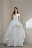 Woman wearing a white strapless gown against a plain background