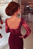Woman wearing a burgundy dress with lace detailing in an indoor setting