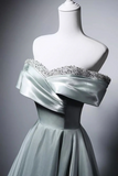 Mint green off-shoulder dress with crystal embellishments on a mannequin against a gray background
