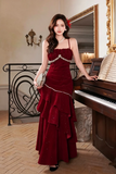 Woman in a red dress standing next to a piano in an elegant room.