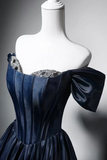 Navy blue evening gown with embellished neckline on a mannequin against a gray background