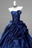 Navy blue evening gown with floral details on a mannequin against a gray background