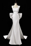 White evening gown with a large bow on a black background