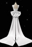 White evening gown with a large bow detail on a black background