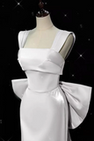 White dress with a large bow on a mannequin against a black background