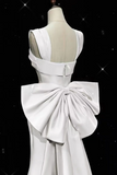White evening gown with a large bow on a black background