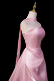Pink satin gown on a mannequin against a black background