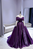 Purple evening gown on a mannequin against a light purple wall.