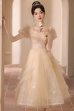 A woman wearing a pale champagne-colored tulle ball gown with sparkling sequins and sheer puff sleeves, standing in a softly lit indoor hallway and holding a small white rose.
