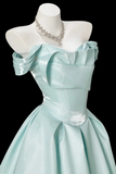 A light aqua off-the-shoulder formal dress displayed on a white mannequin torso, styled with a matching rhinestone necklace against a solid black background.