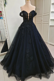 A voluminous off-the-shoulder black ball gown with intricate lace and bead appliques, displayed on a mannequin in an indoor showroom.