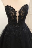 A black formal ball gown with a sweetheart neckline, featuring intricate floral lace applique, sequins, and beadwork on a cream-colored dress form.