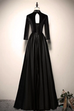 A floor-length black formal gown displayed on a dress form against a plain off-white wall. The dress has three-quarter sleeves, a high mock neck with a keyhole cutout, a lace-up corset-style bodice, and a full satin-like skirt.
