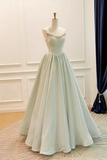 A floor-length formal gown displayed on a mannequin in an indoor room. The dress has a fitted bodice with delicate beaded detailing around the neckline and a full, flowing skirt in a very pale icy blue or off-white tone.