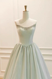 A formal ball gown displayed on a white mannequin dress form against a white paneled wall. The dress has a strapless sweetheart neckline with silver beaded embellishments across the bodice and a full, flowing tulle skirt.