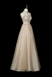 A formal A-line ball gown displayed on a mannequin against a solid black background. The dress features a halter neckline, a heavily embellished beaded bodice in champagne and silver, and a shimmering champagne tulle skirt.