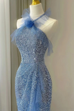 A light blue sequined halter-neck evening gown displayed on a cream mannequin dress form, featuring sheer tulle shoulder details and a matching blue bow at the neckline.