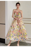 A woman wearing a strapless sweetheart A-line midi dress with a vibrant multicolor floral print on a beige base, standing in an indoor setting.
